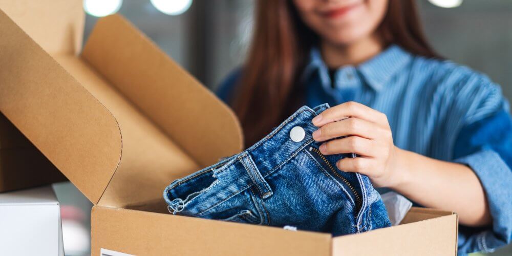 Kobieta otwierająca paczkę kurierską z odzieżą