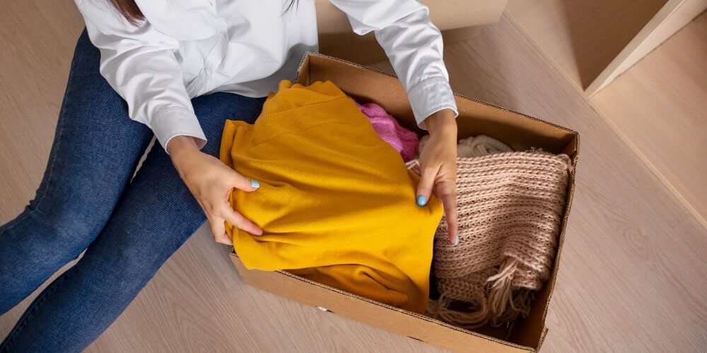 Kobieta pakująca ubrania do paczki kurierskiej