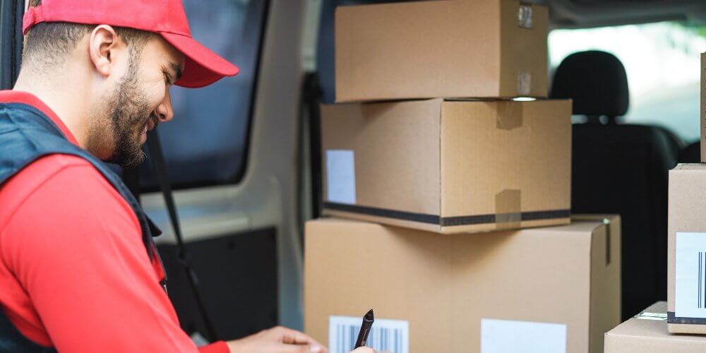 Kurier z paczkami w bagażniku samochodu dostawczego