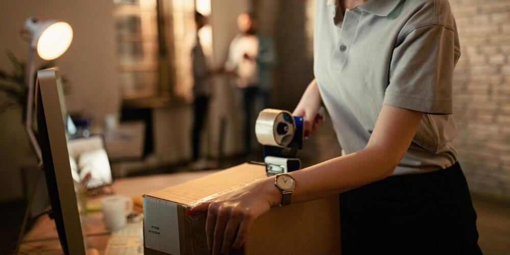 Kobieta w punkcie franczyzy kurierskiej pakująca przesyłkę