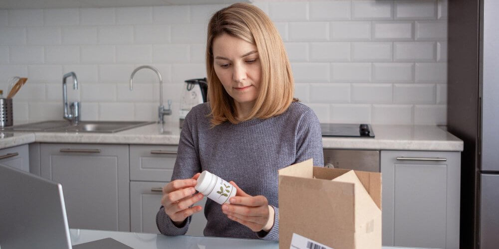 Kobieta otwierająca przesyłkę z suplementami diety